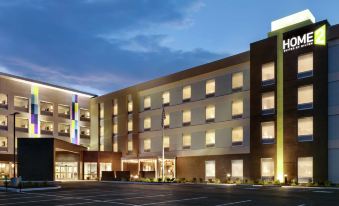 a large hotel building with multiple floors , lit up at night , and a parking lot in front at Home2 Suites by Hilton Easton