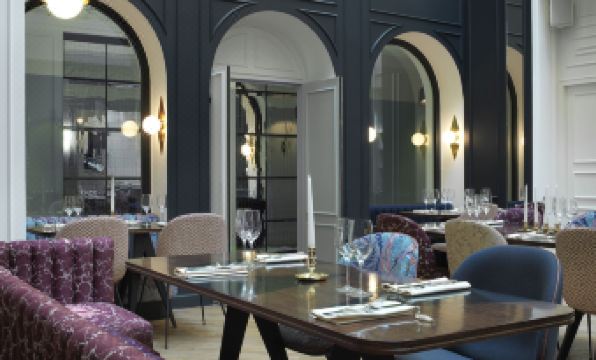 a dining room with a table set for a meal , surrounded by chairs and a couch at Hotel Bachaumont