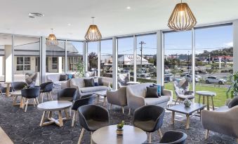 a modern and spacious waiting room with several chairs , couches , and tables arranged around them at Mercure Goulburn