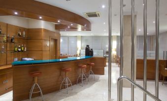 a modern hotel lobby with a large wooden reception desk , several chairs , and a staircase leading to the second floor at NH San Pedro