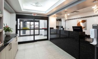 a clean and well - lit hotel lobby with a black marble counter and a glass door at Comfort Hotel