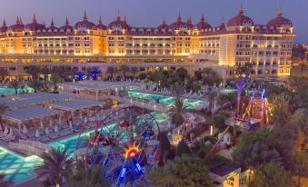 a large hotel with a large pool and amusement park in front of it , illuminated at night at Royal Alhambra Palace