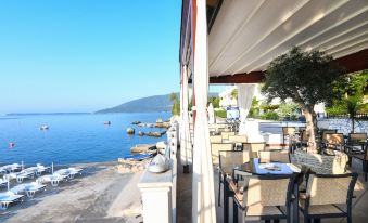 an outdoor dining area near the ocean , with tables and chairs set up for guests at Hotel Perla