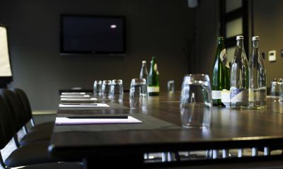 a conference room with several bottles of wine and glasses on a table , along with a television in the background at Village Hotel Liverpool
