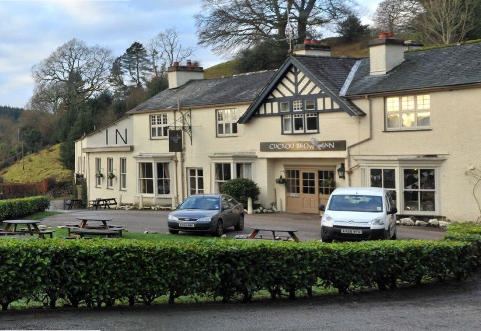 "two cars are parked in front of a large white building with the sign "" inn "" on it" at The Cuckoo Brow Inn