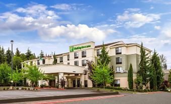 a holiday inn hotel with its name displayed on the building , surrounded by trees and roads at Holiday Inn & Suites Bothell