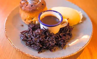 a plate of food with a bowl of sauce , a muffin , and some meat in the center at The Temple Inn