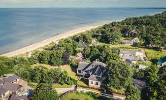 aerial view of a large house surrounded by trees and a beach , with the ocean in the background at Sunrise Beach Villa