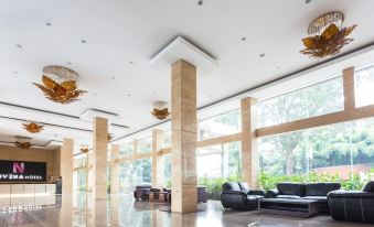 a large , modern hotel lobby with a large glass wall and several couches and chairs at Novena Hotel Bandung