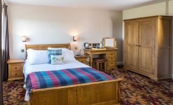 a hotel room with a wooden bed , a desk , and a bathroom next to it at Three Horseshoes Inn