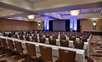 a large conference room with rows of chairs arranged in a semicircle , and a projector on the wall at Hilton Concord