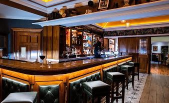 a well - decorated bar with a wooden bar counter , several chairs , and a tv mounted on the wall at Clanard Court Hotel