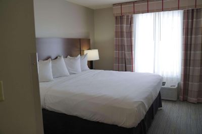 a large bed with white sheets and pillows is in a room with a window at Country Inn & Suites by Radisson, Watertown, SD