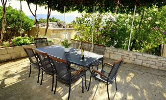 an outdoor dining area with a table and chairs set up for a meal , surrounded by a lush garden at Lolita