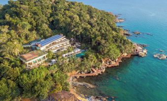 a bird 's eye view of a resort nestled on a rocky shore with clear blue water and lush green trees at Six Senses Krabey Island