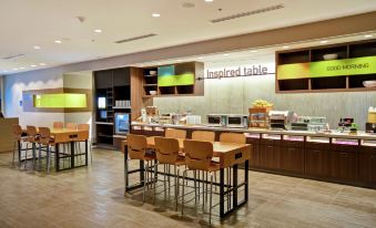 a restaurant with a long counter , where several people are seated and enjoying their meals at Home2 Suites by Hilton Walpole Foxboro