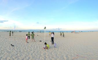 a group of people , including children , are playing on a sandy beach near the ocean at Sepon Boutique Resort