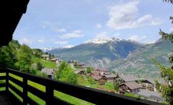 a view from a balcony , looking out at a mountainous landscape with snow - capped peaks and wooden houses at Chalet Ninette