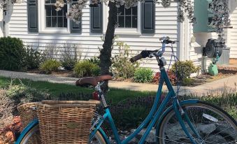 a blue bicycle with a basket attached to the front is parked in front of a white house at The Homestead