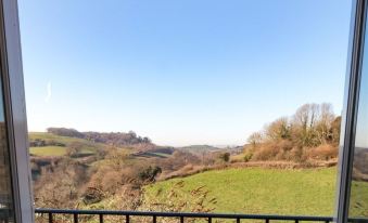 a beautiful view of a hilly landscape with a clear blue sky , and a black railing in the foreground at Three Horseshoes Inn