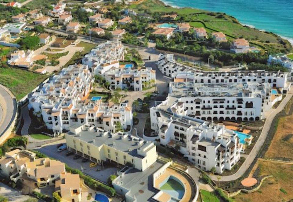 a bird 's eye view of a complex resort with multiple buildings , pools , and golf courses at Belmar Spa & Beach Resort