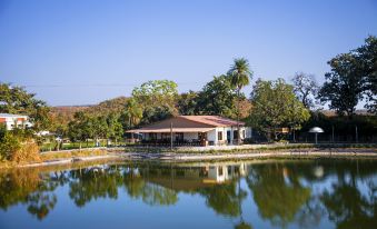 a small building is situated near a lake with trees and mountains in the background at Graces Resort