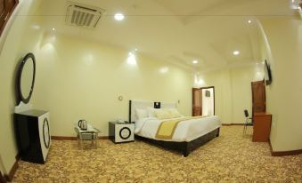 a large bed with white linens is in a room with a beige carpet and a white chair at Fatima Hotel