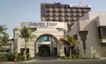 a grand hotel building with a large archway entrance and palm trees in front of it at Golden Hotel