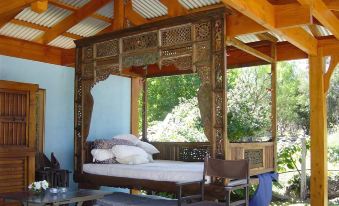 a bed with a wooden canopy is situated in a gazebo , surrounded by trees and foliage at Riverhouse at Howqua Dale