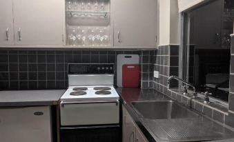 a modern kitchen with stainless steel appliances , including a refrigerator , oven , and sink , along with a dining table and chairs at Prince of Wales Hotel