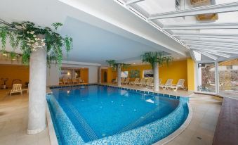 an indoor swimming pool surrounded by a hotel , with people enjoying their time in the pool at Hotel Italia