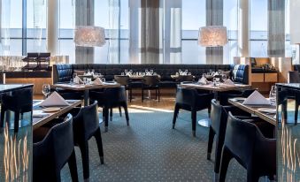 a large dining room with multiple tables and chairs arranged for a group of people to enjoy a meal together at Hilton Helsinki Airport