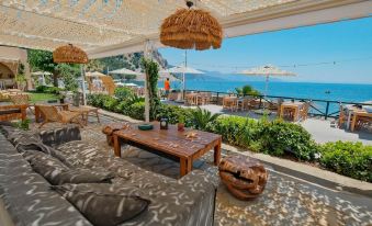 a patio with a wooden table and chairs , surrounded by potted plants and an ocean view at The Diplomat Hotel