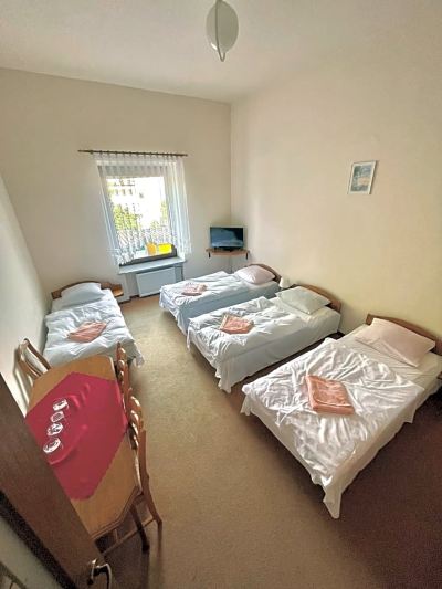 a hotel room with four beds arranged in a row , each with a pink pillow on it at Titanic