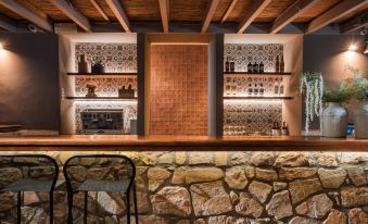 a stone wall is next to a bar with shelves of bottles and glasses on display at Megisti Hotel