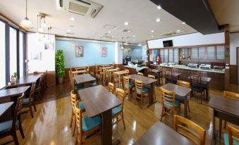 a large dining room with wooden tables and chairs , a long counter , and a tv on the wall at Country Hotel Takayama