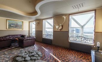 a room with a large window , brown couch , and floor made of pebbles in front of large windows at Hotel Blonduos