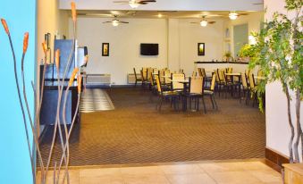 a large room with multiple tables and chairs , a counter , and a tv on the wall at The Classic Desert Aire Hotel