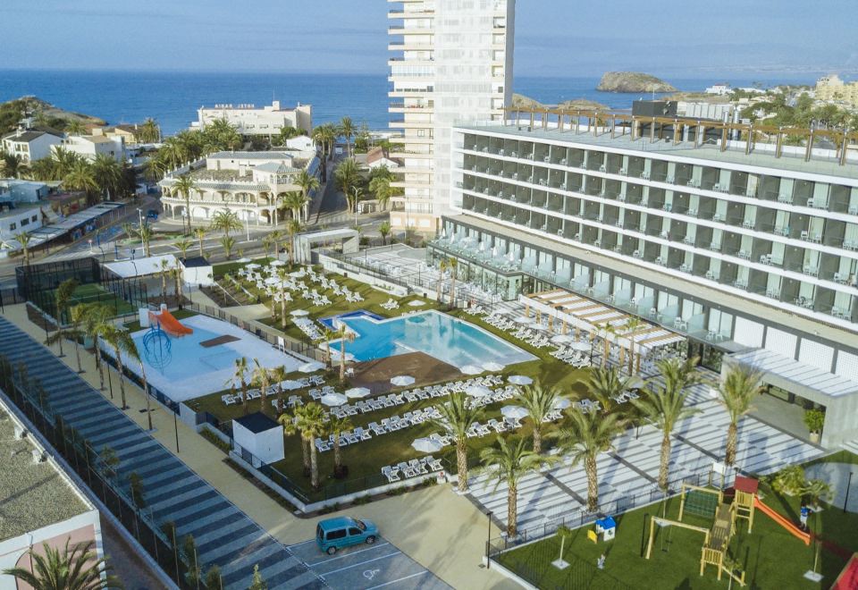 an aerial view of a large hotel with a pool surrounded by palm trees and the ocean in the background at Hotel Dos Playas