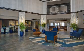 a modern hotel lobby with wooden floors , large columns , and blue couches arranged around a coffee table at Homewood Suites by Hilton Chicago-Lincolnshire