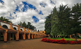 a long , modern building with orange walls and a red roof is surrounded by trees and bushes at Hotel Pineta