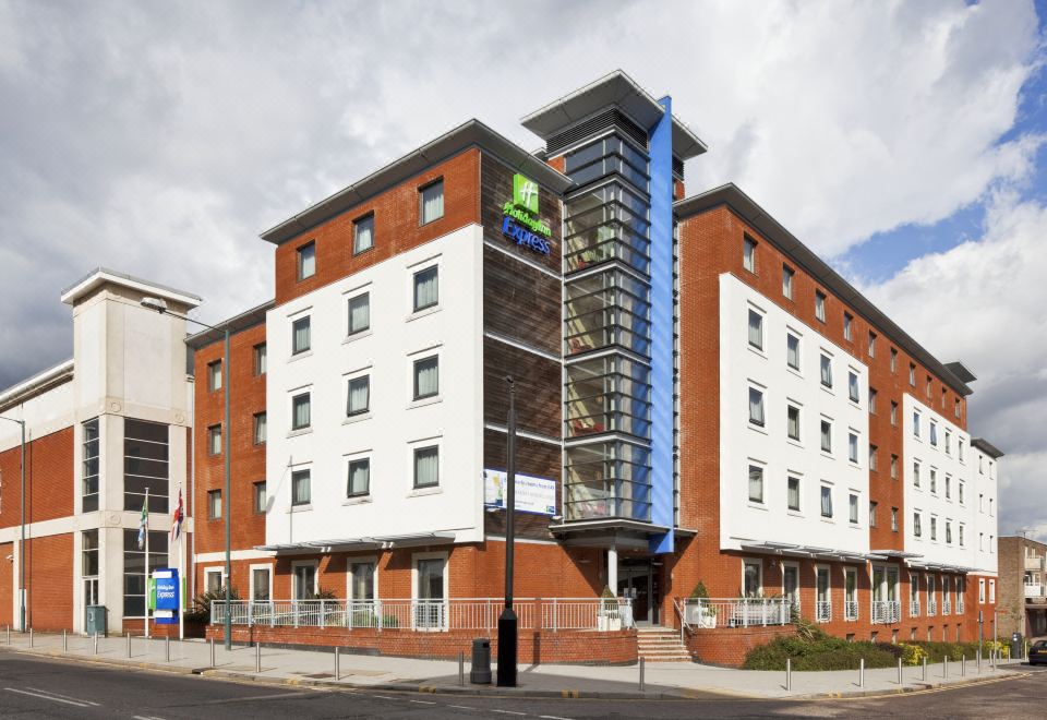 a brick building with a large green sign on the side , located on a city street at Holiday Inn Express Stevenage