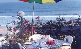 Another beach setup includes a table with chairs and an umbrella nearby at Hotel Sonali
