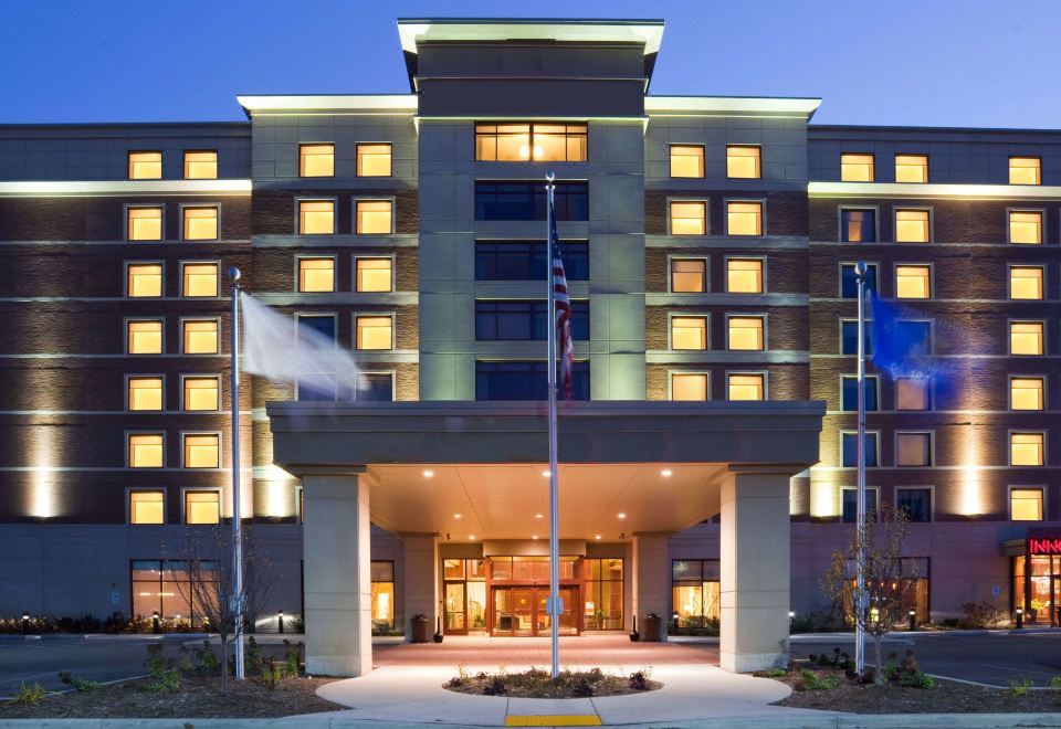 a large hotel with multiple flags flying outside , creating a festive atmosphere for guests at Sonesta Milwaukee West Wauwatosa