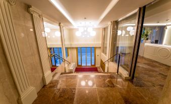 a grand foyer with a red carpeted floor , white walls , and a large window overlooking the ocean at Hotel Geneva by Fassbind
