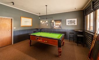 a pool table is in the center of a room with gray walls and wooden furniture at Great Lake Hotel