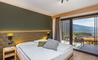 a large bed with white linens is in a room with a sliding glass door leading to a balcony at Miravalle