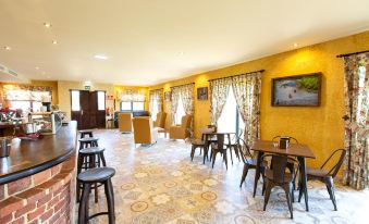 a large , well - lit room with yellow walls and a tiled floor features multiple tables and chairs at Hotel Cerro La Nina