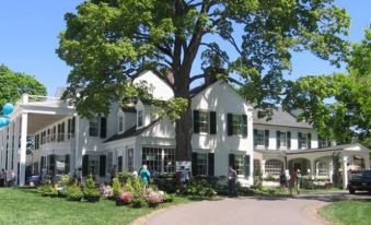 a large white building surrounded by green grass and trees , with a group of people standing in front of it at Residence Inn Hartford Avon