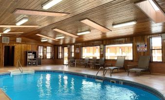 an indoor swimming pool surrounded by wooden walls , with several chairs placed around the pool area at Goulding's Lodge